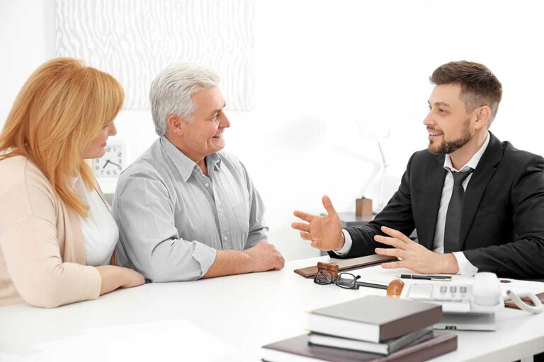 Young parents and a baby sitting together at a kitchen table, reviewing documents and insurance papers.