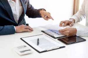 Adult reviewing life insurance documents beside medication bottles and a notebook at a kitchen table.