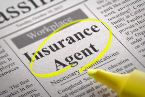 A person reviews a household insurance bill with charts and paperwork spread out on a kitchen table.